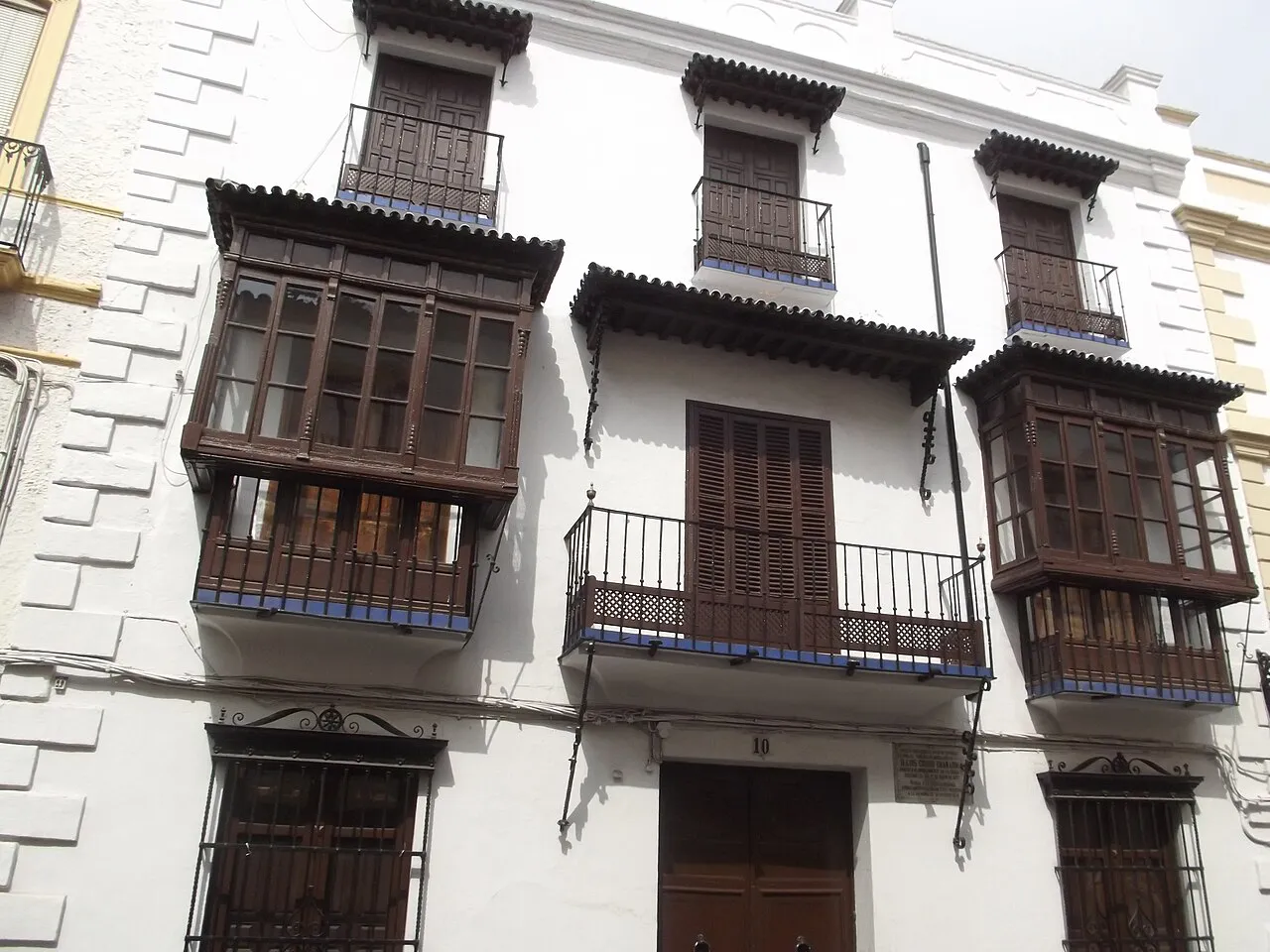 Whitewashed townhouse with dark wooden enclosed balconies on Calle Armiñán in Ronda's old town
