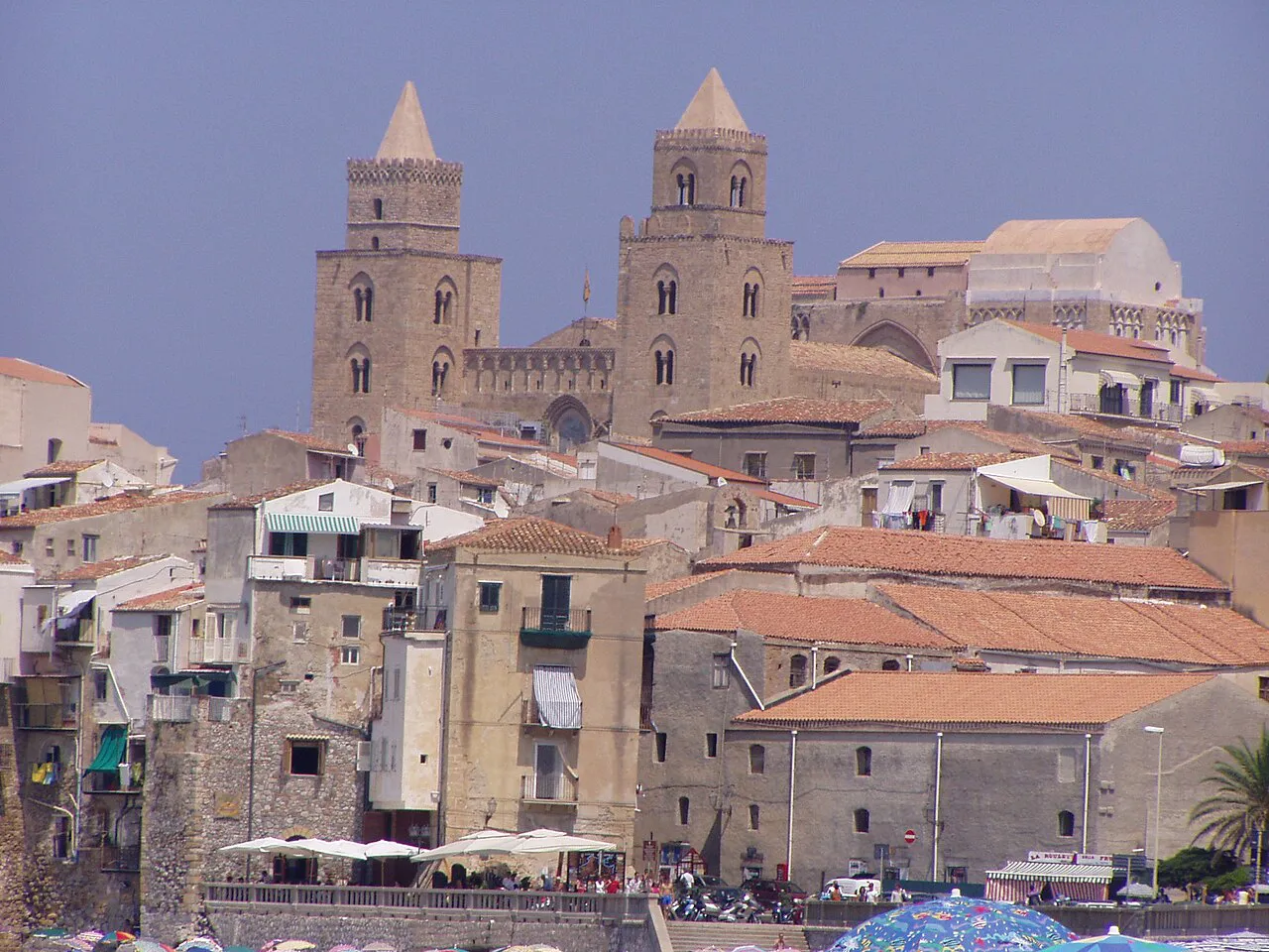 The twin Norman towers of Cefalù Cathedral rising above the old town's stone houses and terracotta roofs, Sicily