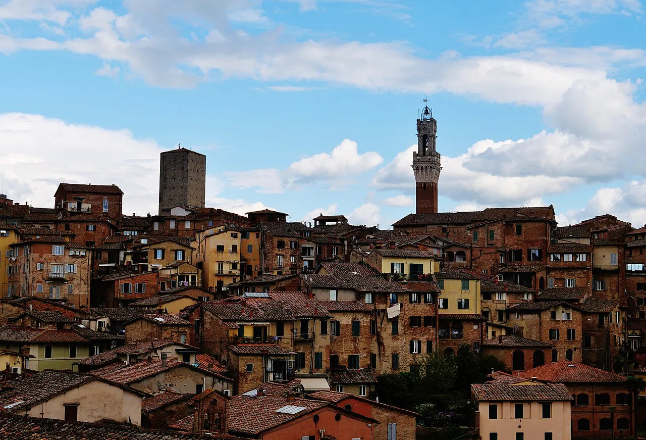 Tightly packed brick houses of Siena climbing a hill toward the Torre del Mangia