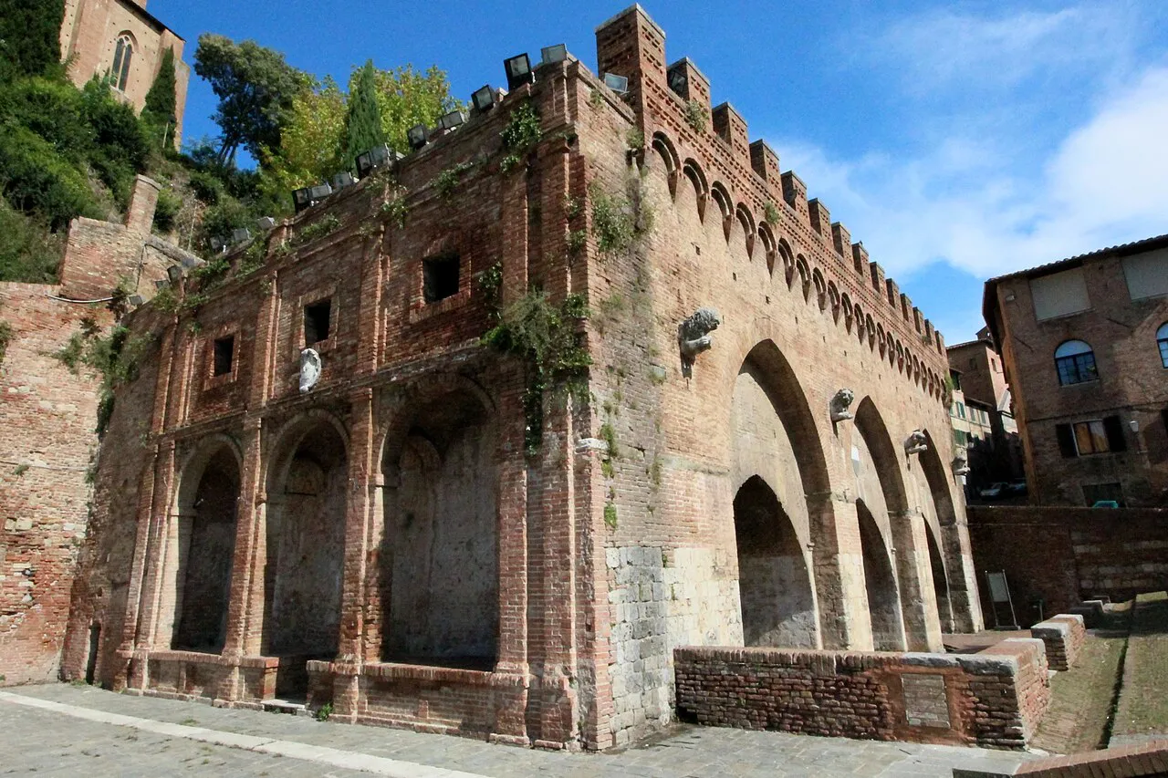 The brick arcades and crenellations of the medieval Fontebranda fountain in Siena