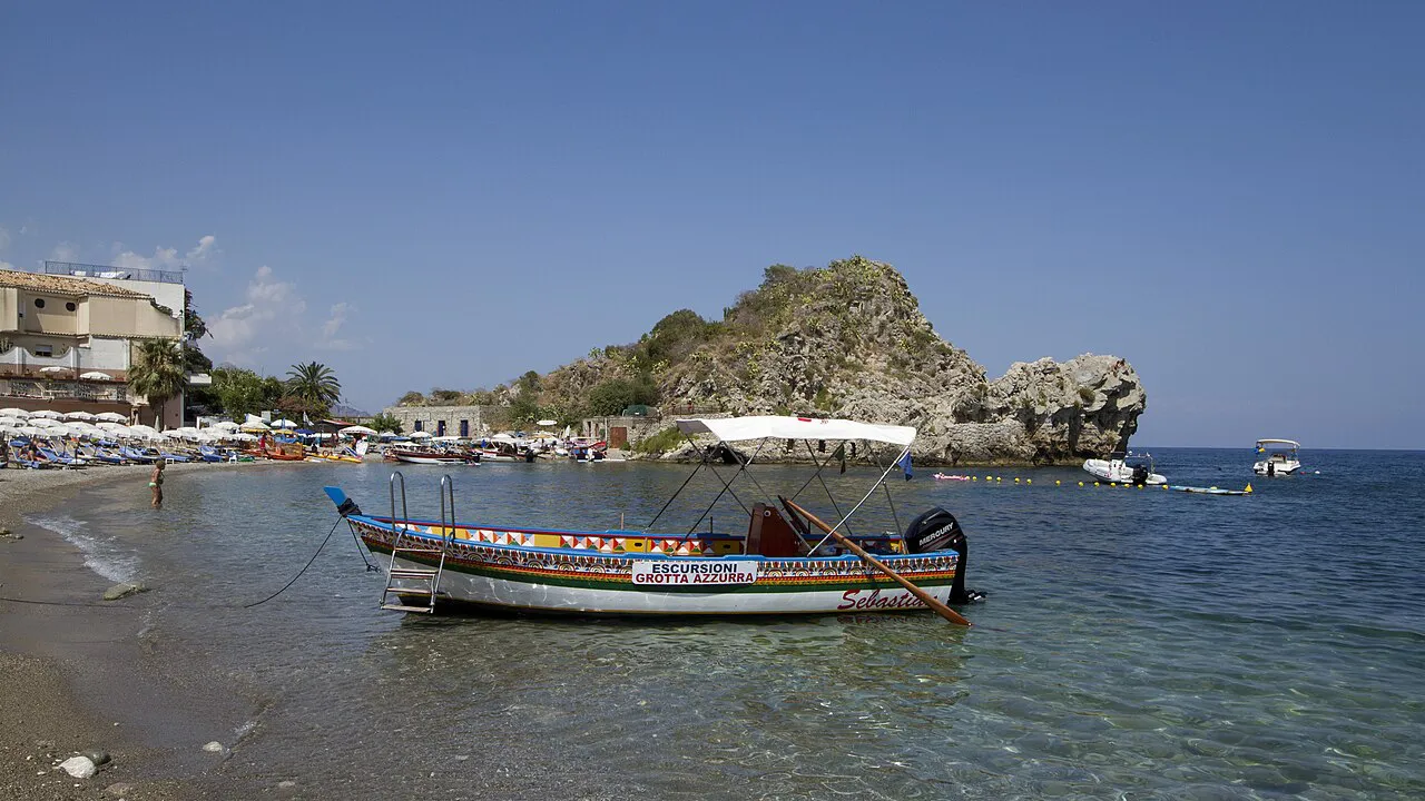 A traditional wooden boat moored near the rocky islet of Isola Bella in the bay of Mazzarò below Taormina