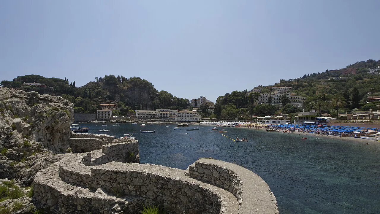 Curving stone wall above the sheltered bay and beach of Mazzarò near Taormina