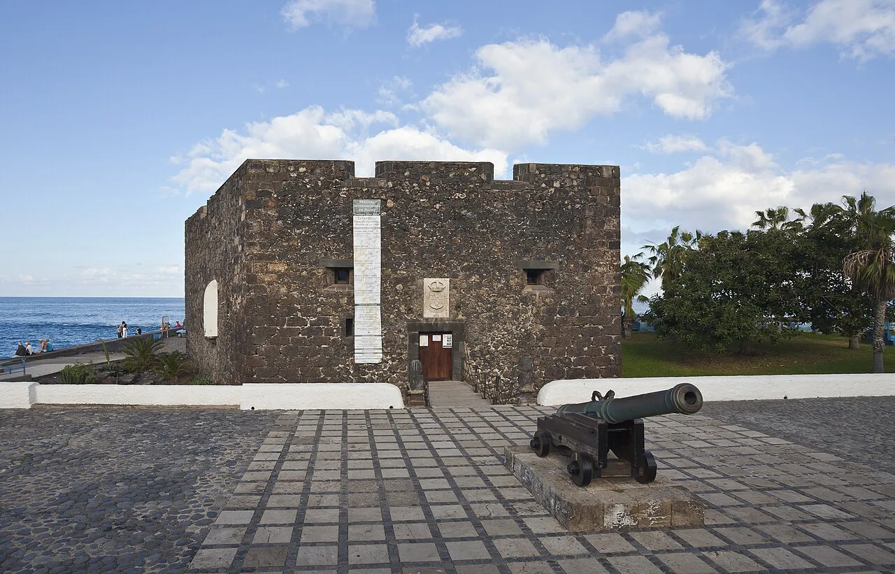 Dark volcanic-stone walls of Castillo San Felipe with an old cannon by the sea in Puerto de la Cruz, Tenerife
