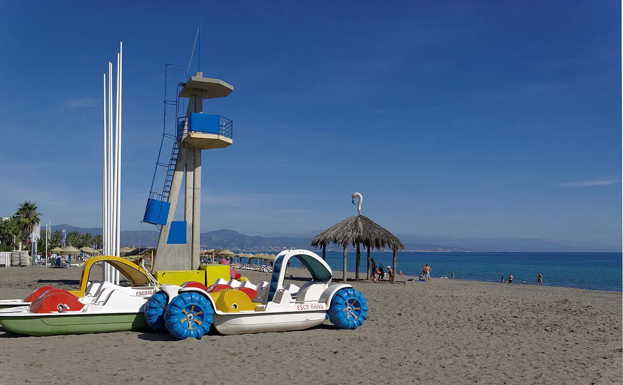 Pedal boats and a lifeguard tower on the sandy beach at Torremolinos with the coast stretching beyond