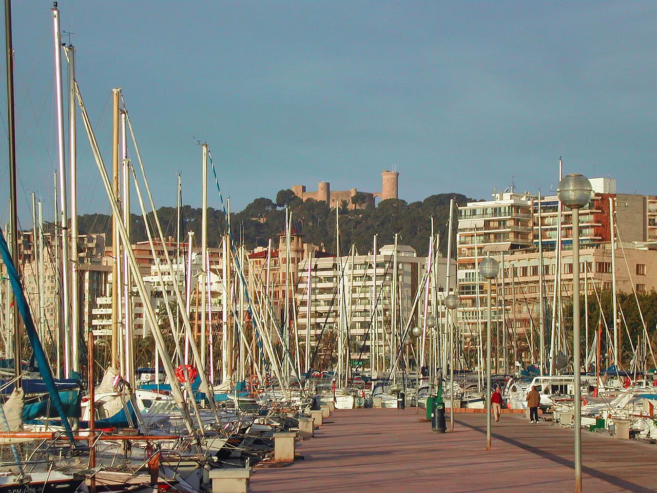 Sailing-boat masts in the marina on Palma’s Passeig Marítim, with Bellver Castle on the wooded hill