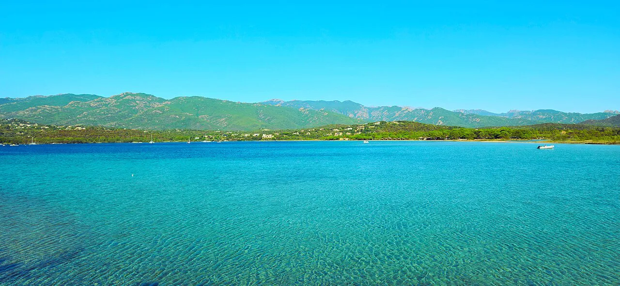 Clear turquoise water of the Gulf of Porto-Vecchio with green hills and mountains beyond