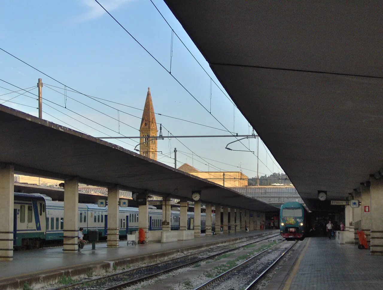 Platforms and trains at Firenze Santa Maria Novella station, with the basilica bell tower beyond