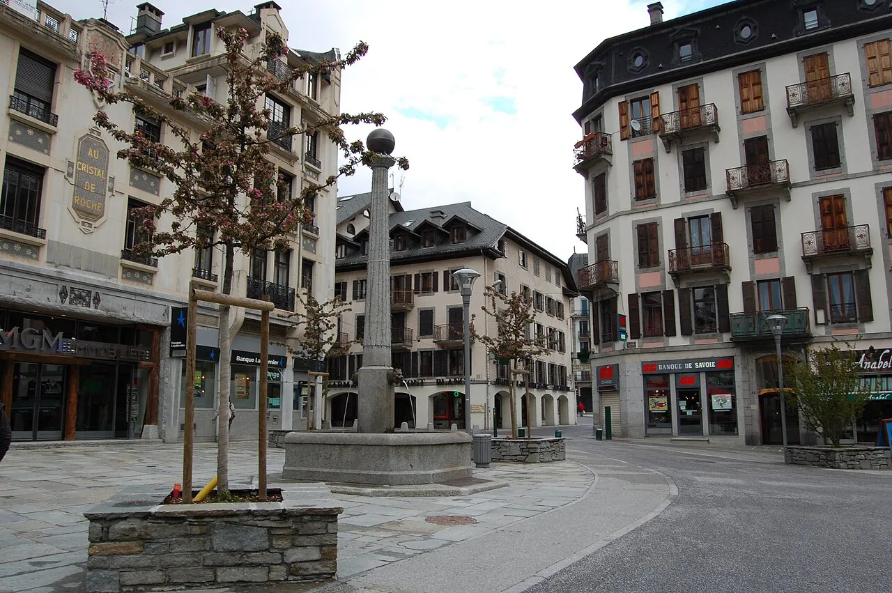 Stone obelisk fountain on Place Balmat in central Chamonix, ringed by decorated old facades