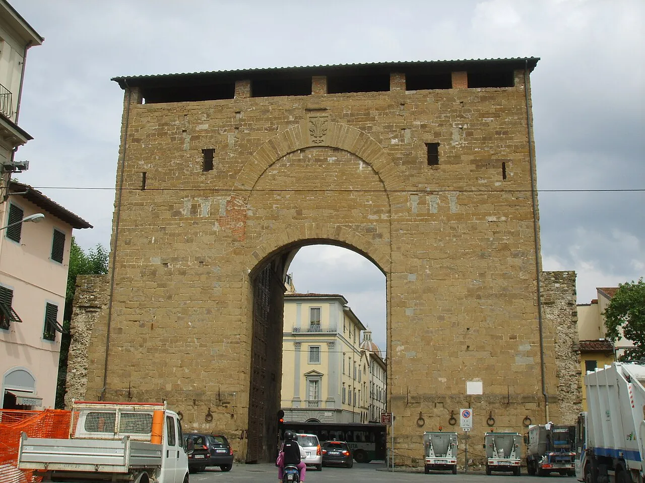 The tall medieval stone gate of Porta San Frediano in Florence, with traffic passing through its arch