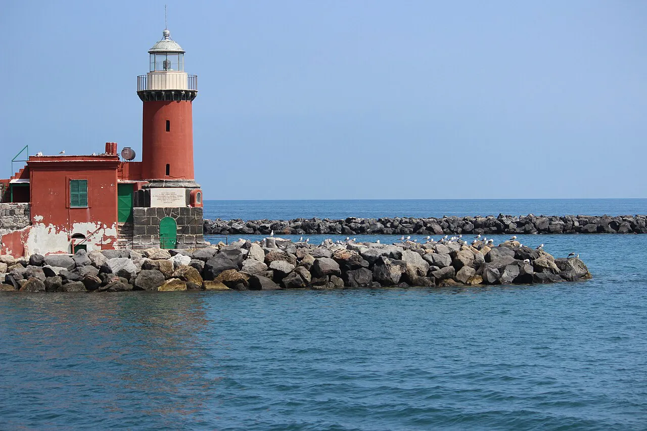 Red lighthouse on the stone breakwater at the harbour entrance of Ischia Porto