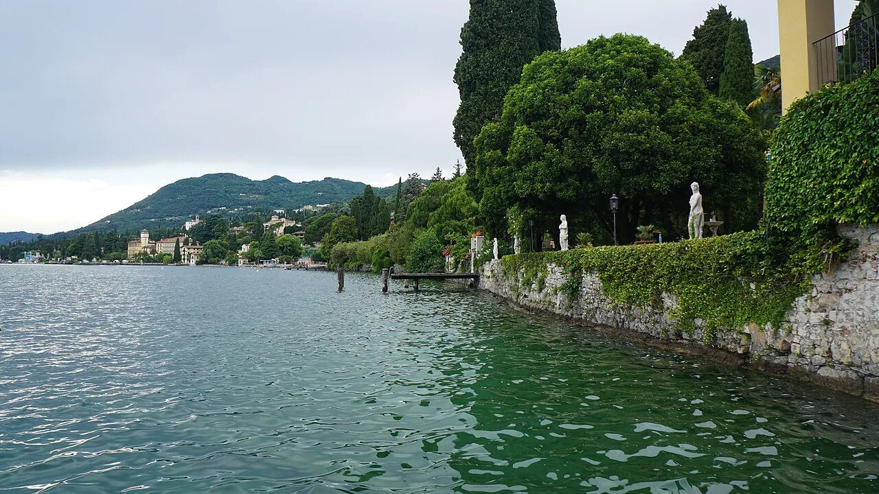 Cypress-lined garden wall along the green lake edge at Fasano di Gardone Riviera, Lake Garda