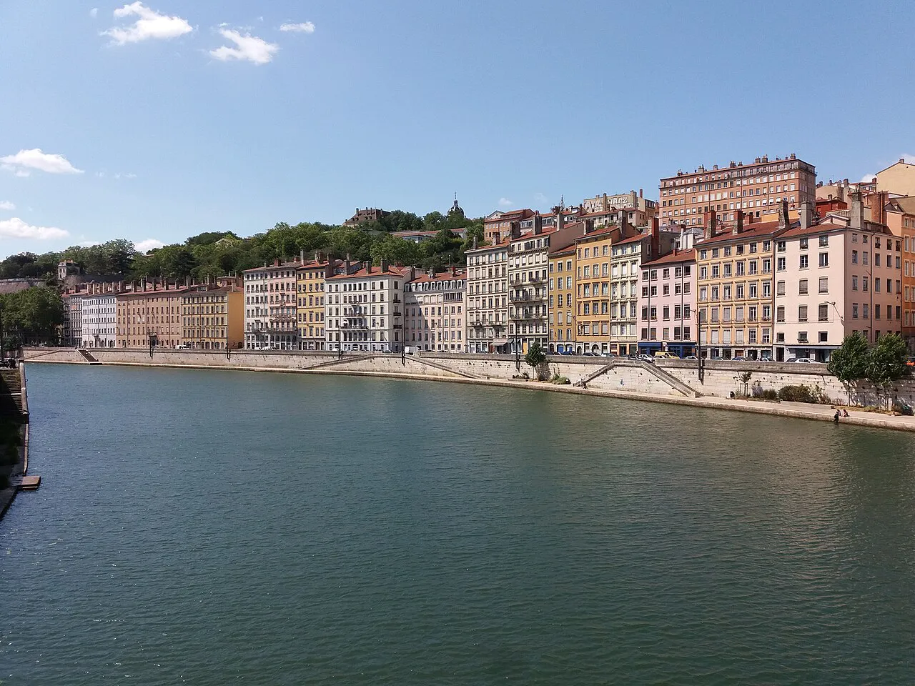 Colourful facades along Quai Saint-Vincent curving beside the Saône in Lyon under a blue sky