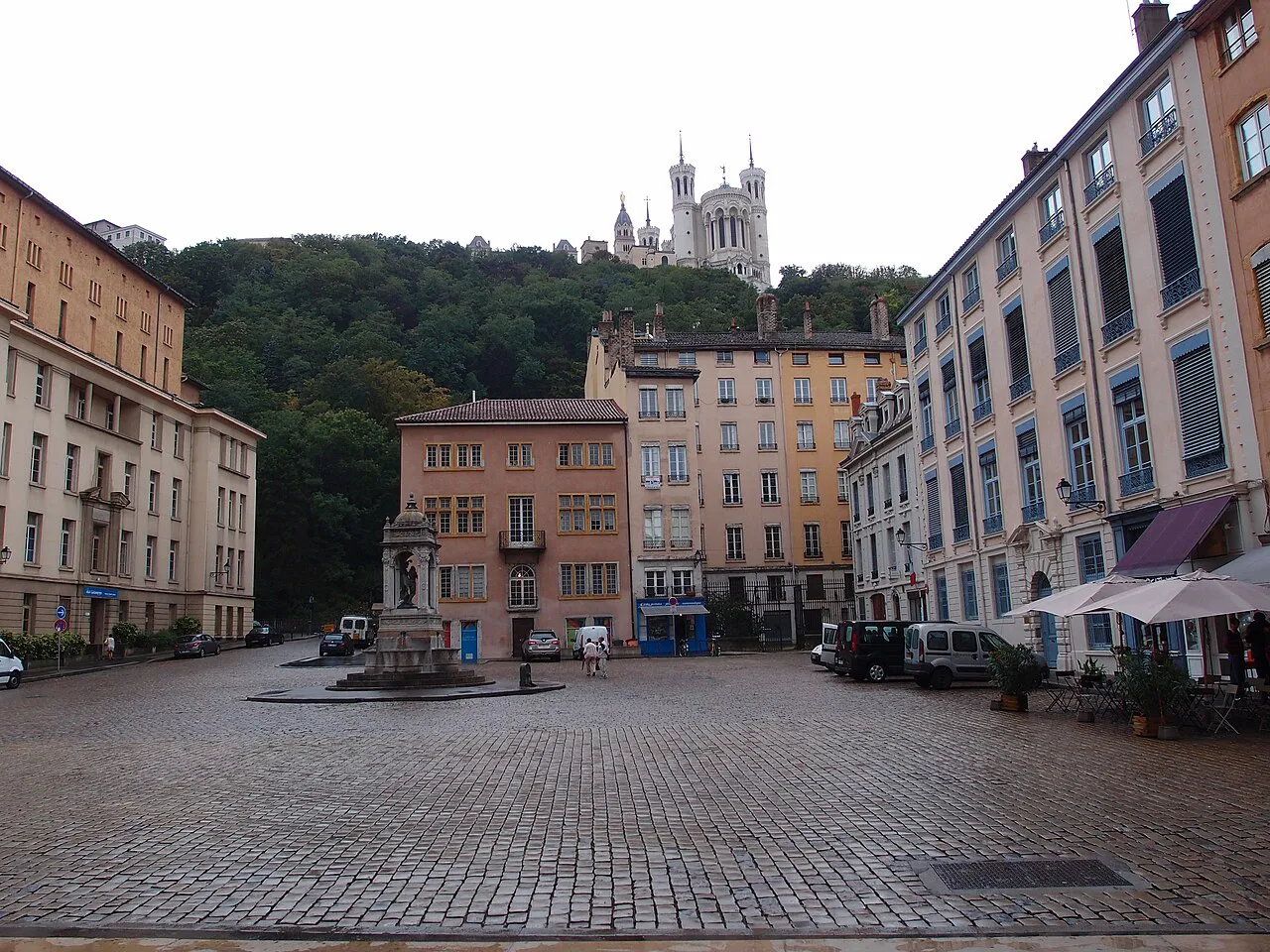 Cobbled Place Saint-Jean in Vieux Lyon with its fountain, framed by old facades and Fourvière above