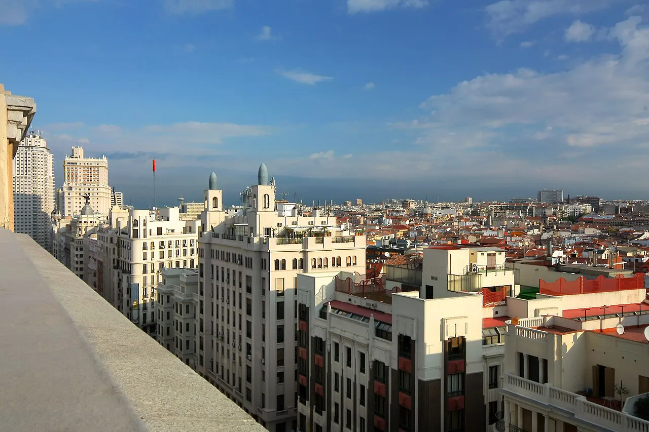 Elevated daytime view over Gran Vía buildings and Madrid rooftops toward the horizon