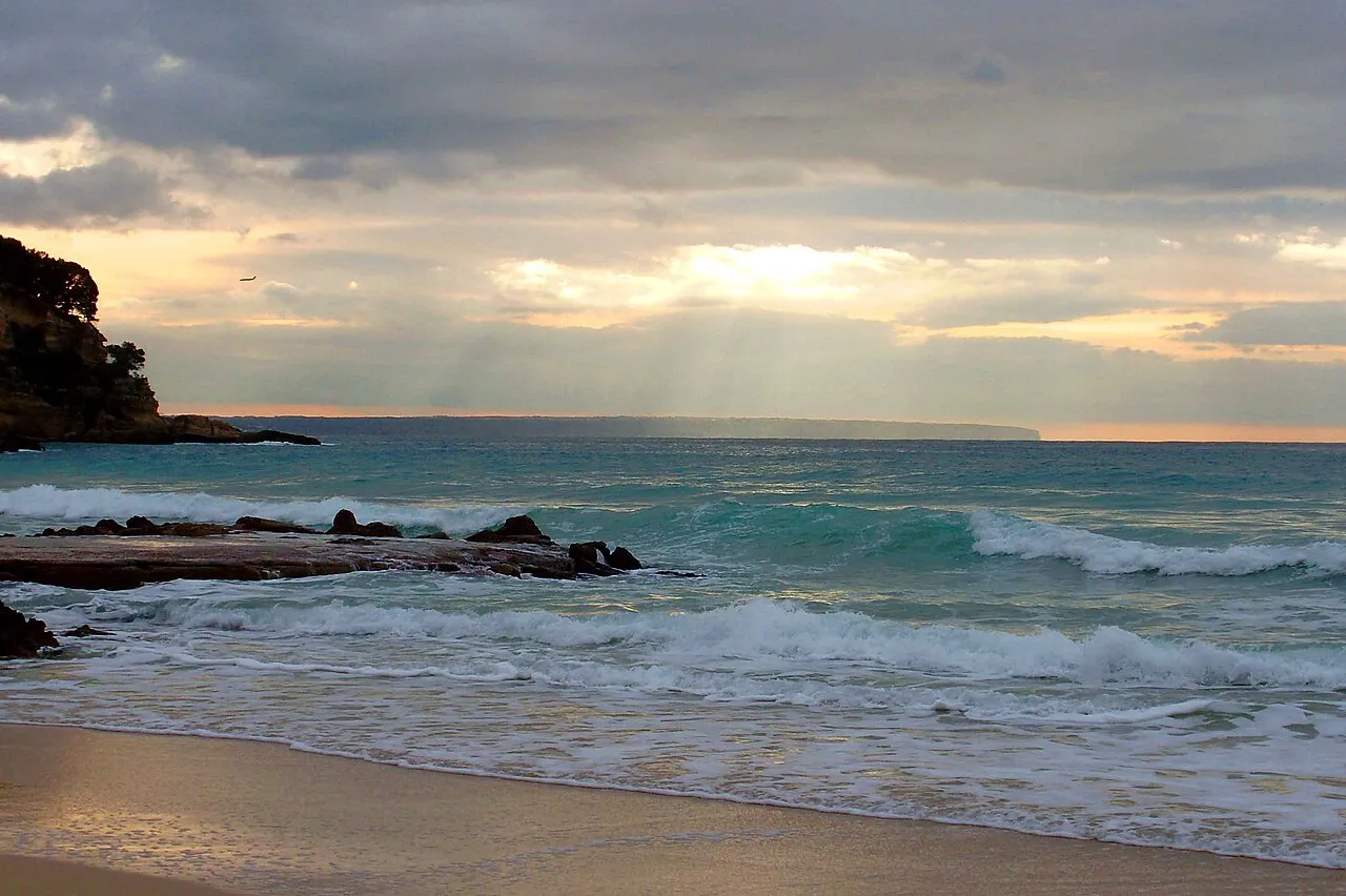 Waves breaking on the sand at Cala Major in Palma under a cloudy winter sky