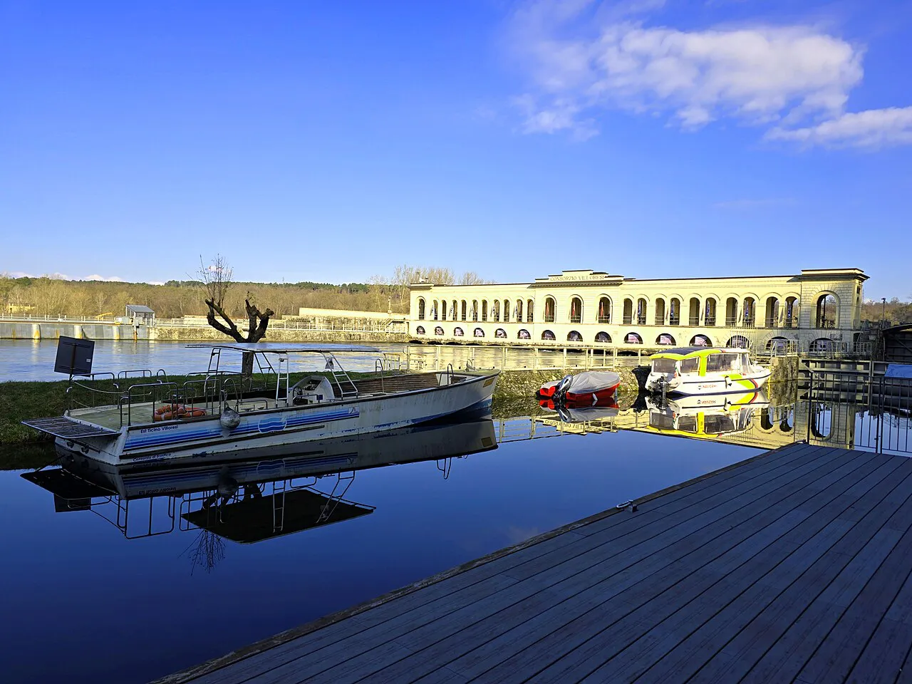 Still canal water and moored boats at the Panperduto Dam in Somma Lombardo, near Malpensa
