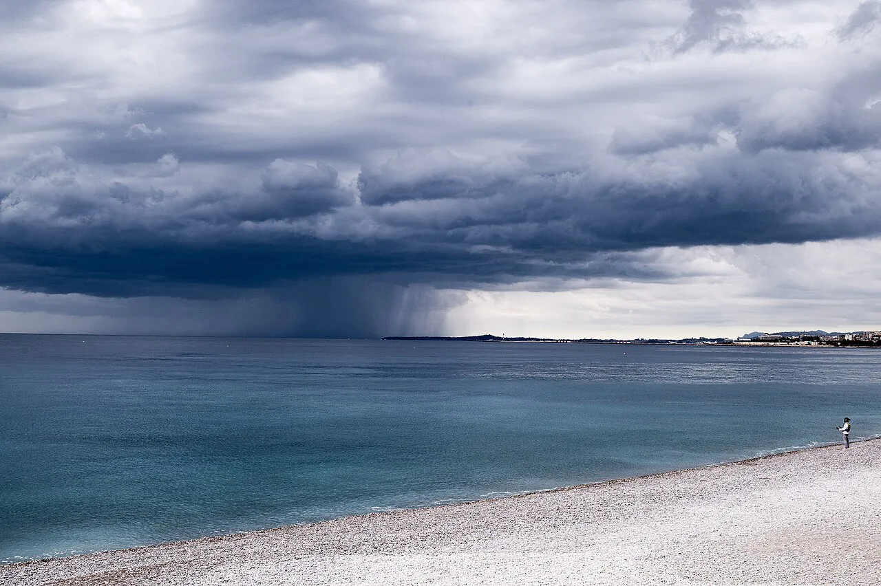Storm clouds gathering over the Baie des Anges and the pebble beach in Nice