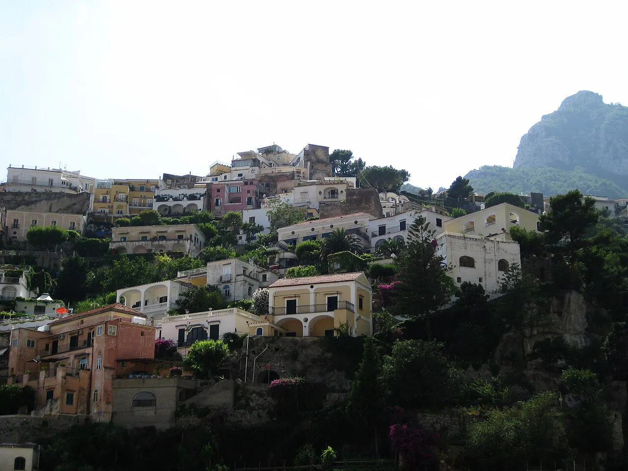 Terraced houses and gardens stacked on the steep hillside of Positano below a rocky peak