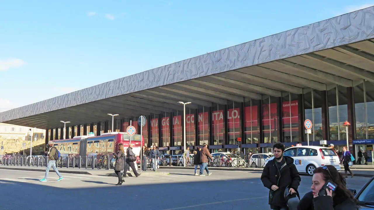 Long canopy of the Roma Termini station front facing Piazza dei Cinquecento under a blue sky