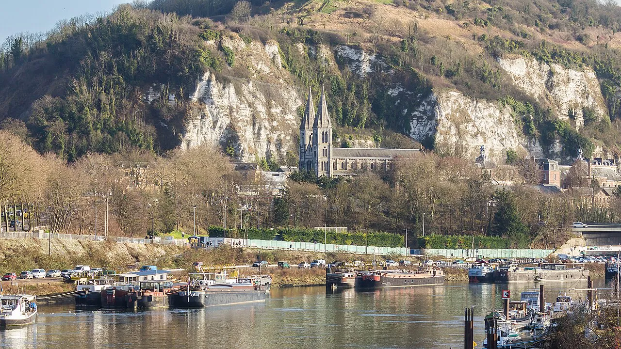 Barges moored on the Seine at Rouen below the chalk cliffs and Bonsecours basilica