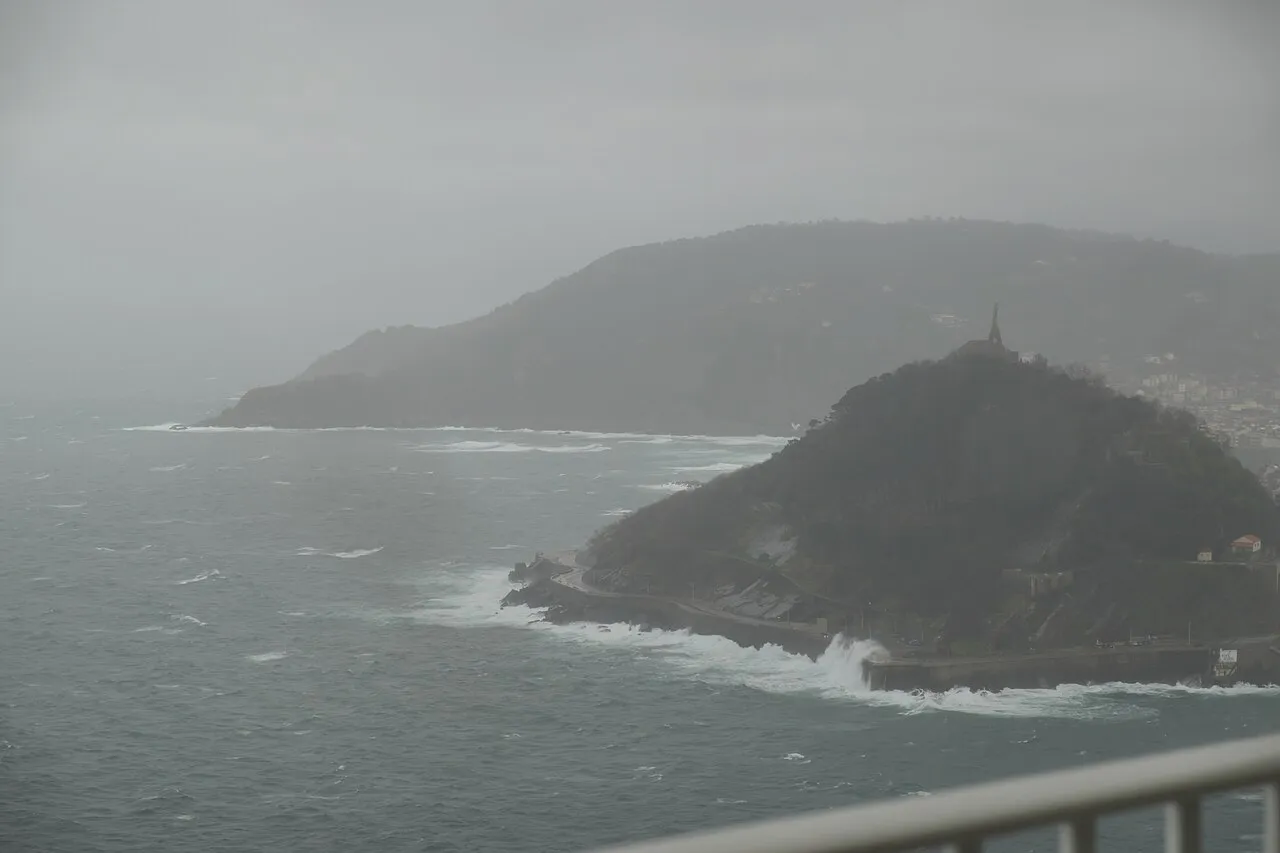 Santa Clara island and Monte Urgull in La Concha Bay under grey skies, seen from Monte Igueldo, San Sebastián