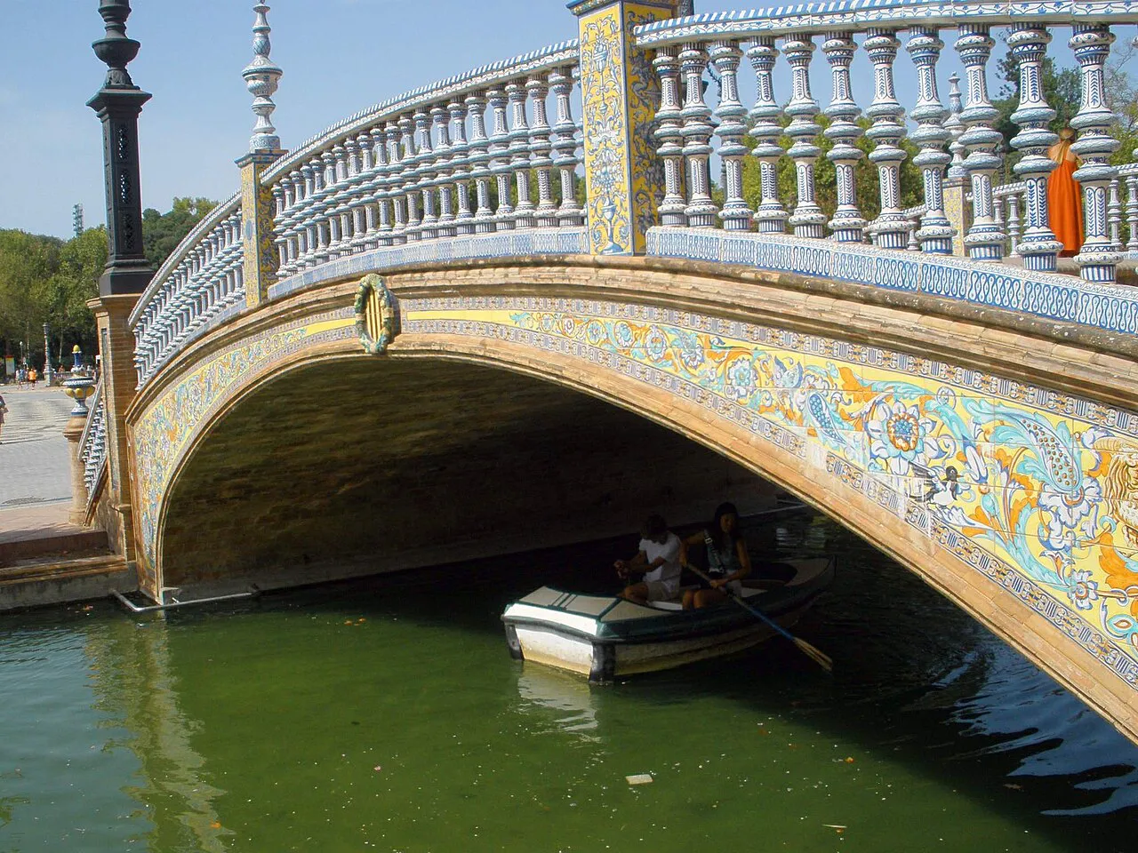 A tiled ceramic bridge with white balustrades crossing the canal at Plaza de España, Seville
