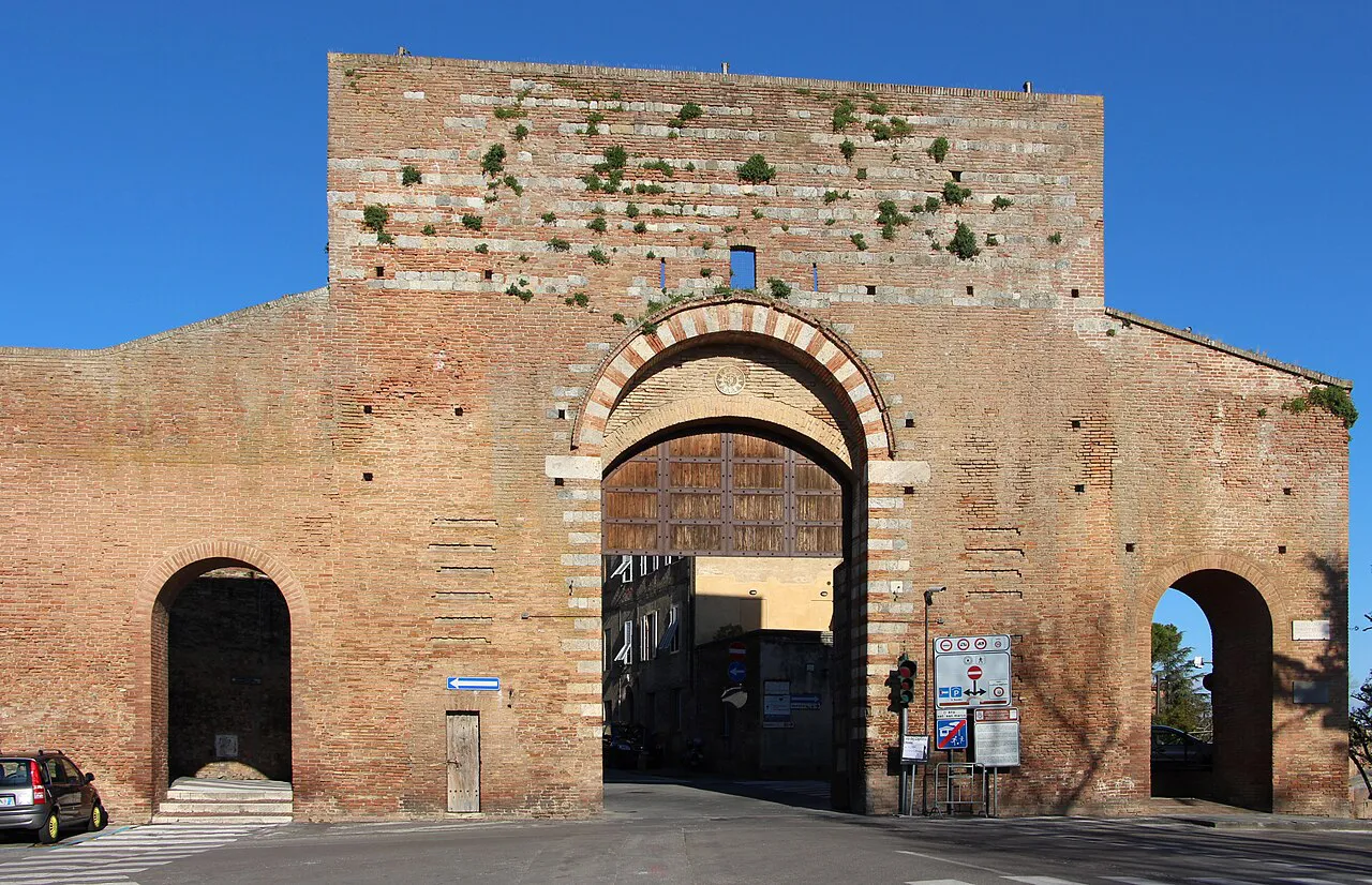 The arched brick Porta San Marco gateway in Siena's medieval city walls under a deep blue sky