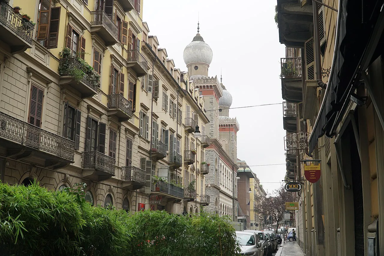 Residential street in Turin's San Salvario district near Porta Nuova, with the domes of the synagogue beyond