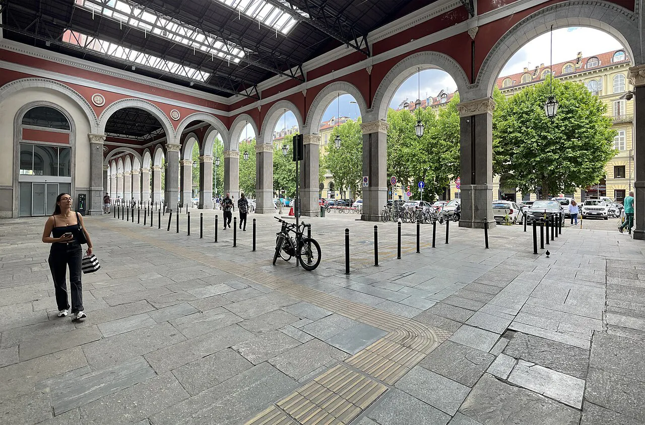 Red-arched side gallery of Torino Porta Nuova station opening onto the street