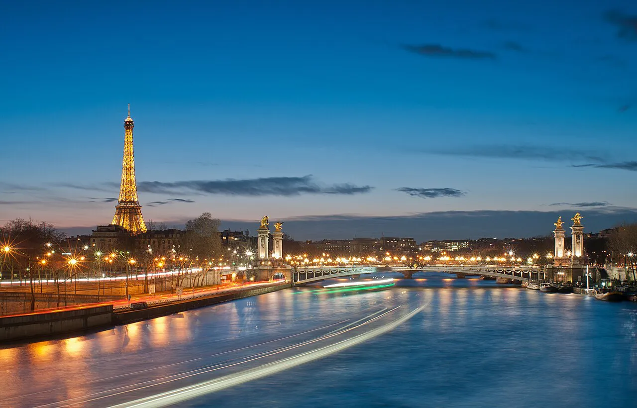 The Eiffel Tower and Pont Alexandre III lit up at dusk over the Seine in Paris