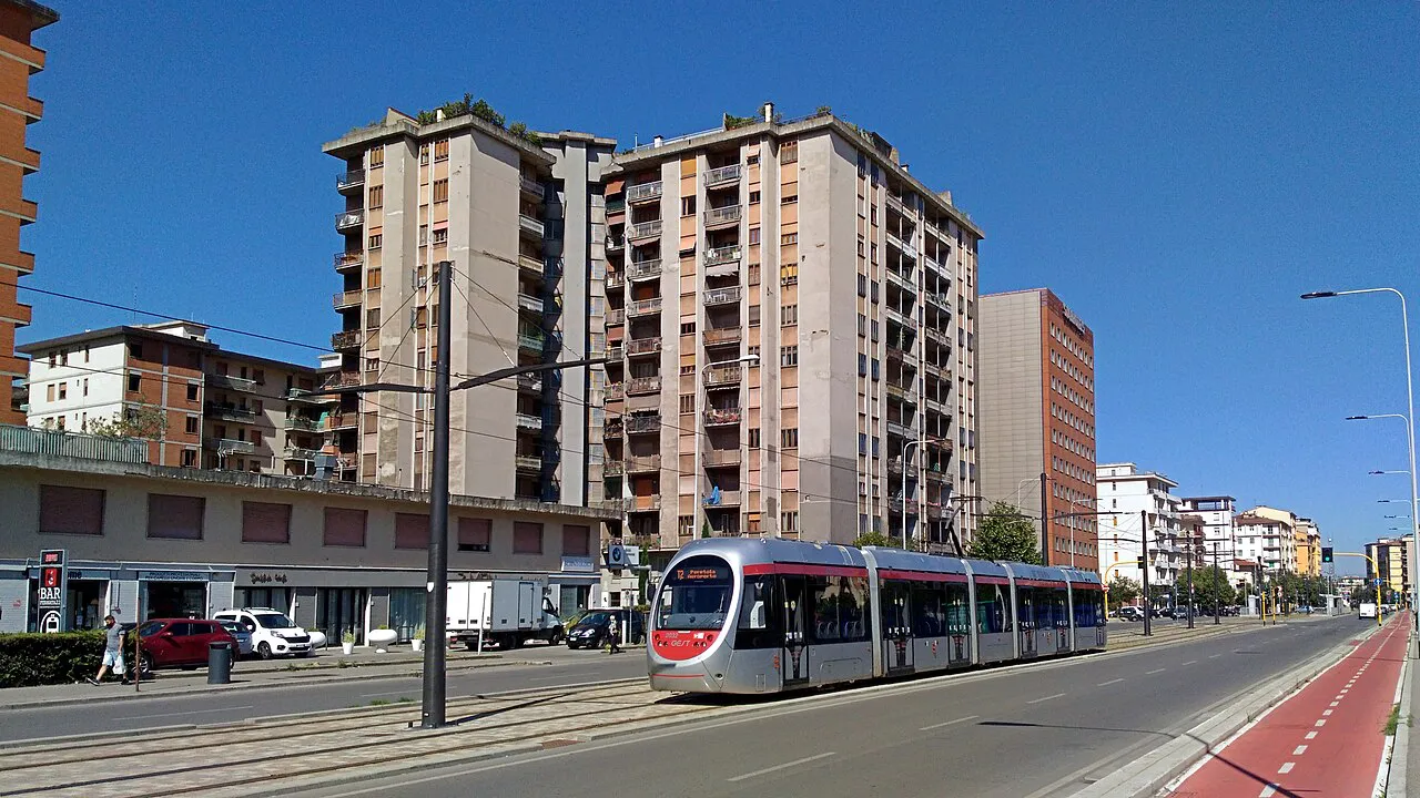 A modern tram running along Via di Novoli in Florence beside apartment blocks
