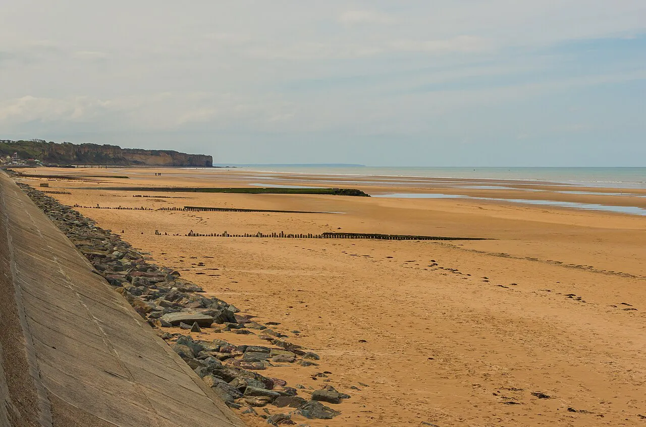 Wide sandy Omaha Beach seen from the Dog Red sector, with the sea wall and bluffs beyond