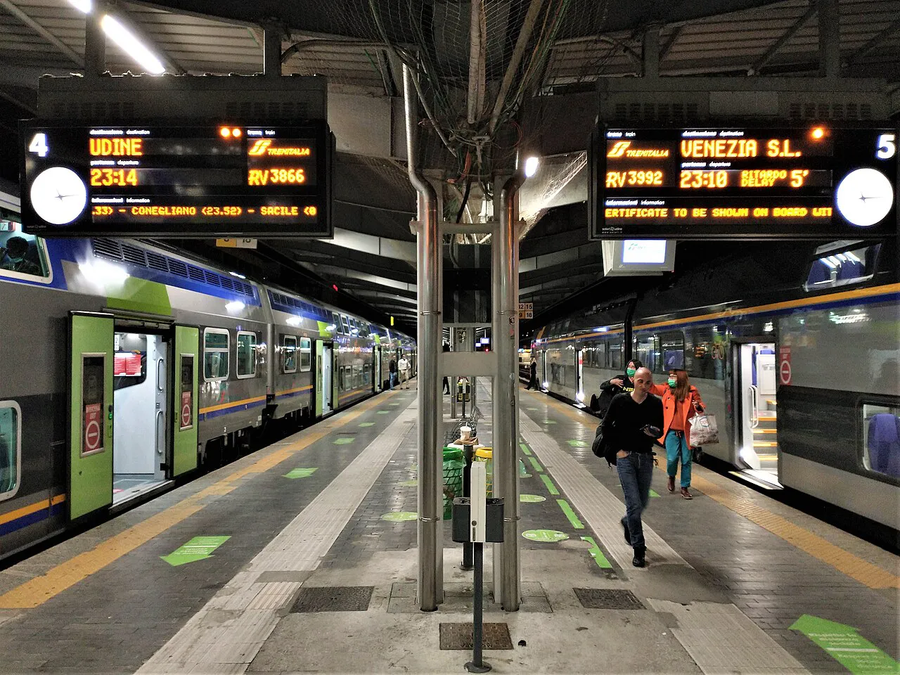 Platform at Venezia Mestre station with regional trains and departure boards overhead