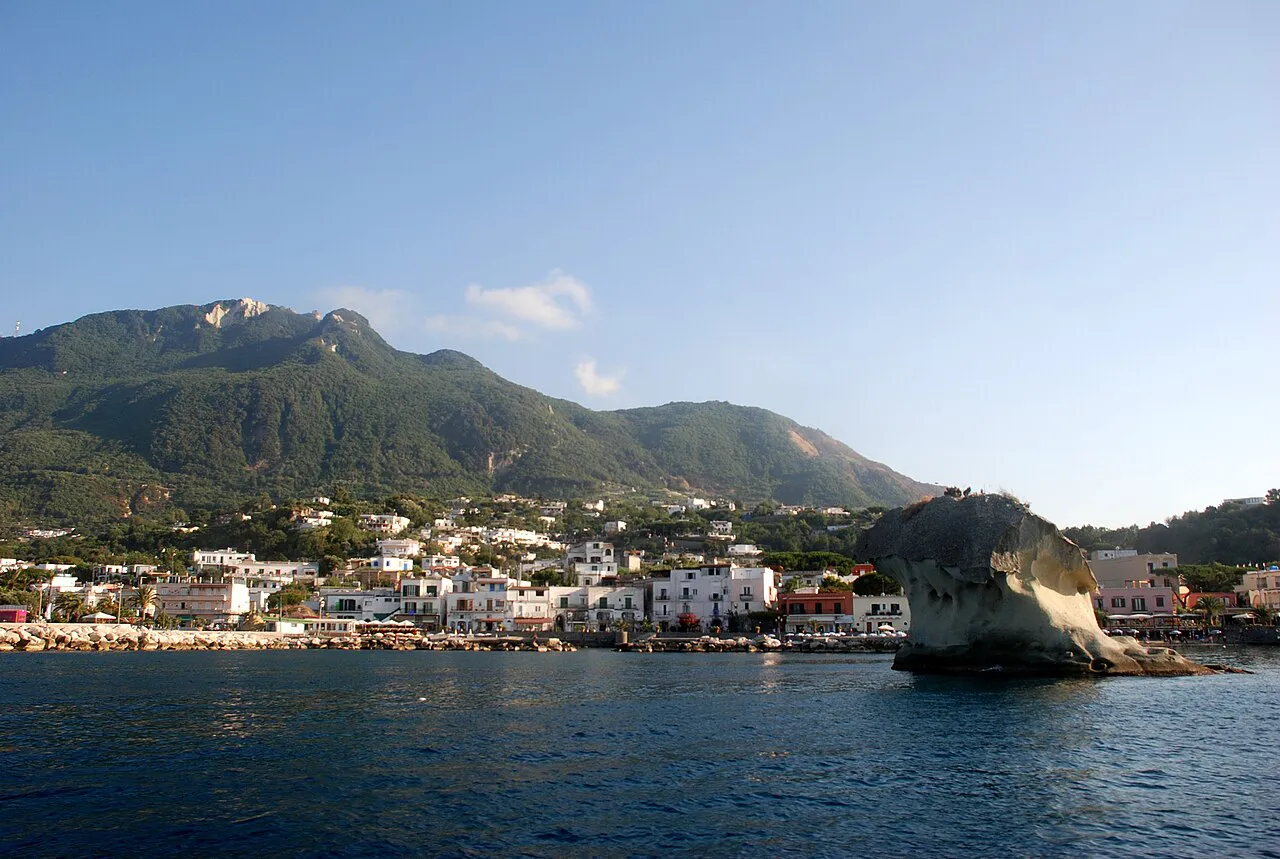 Lacco Ameno's seafront and the mushroom-shaped Fungo rock below green hills on Ischia