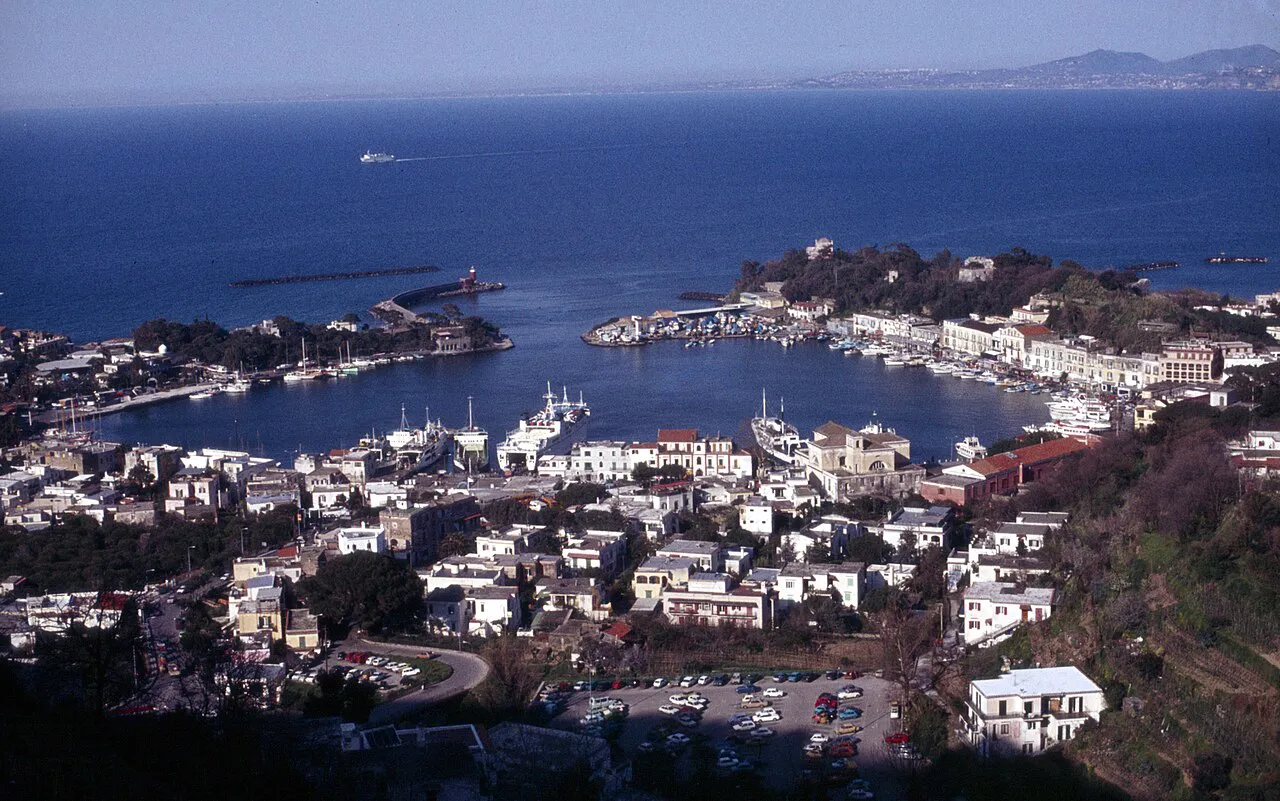 Elevated view over the round harbour basin of Ischia Porto, its quays and the surrounding town
