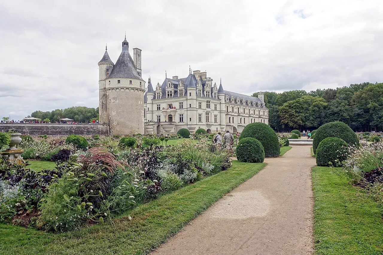 Flower beds and clipped shrubs in the gardens of the Château de Chenonceau, with the round Tour des Marques behind