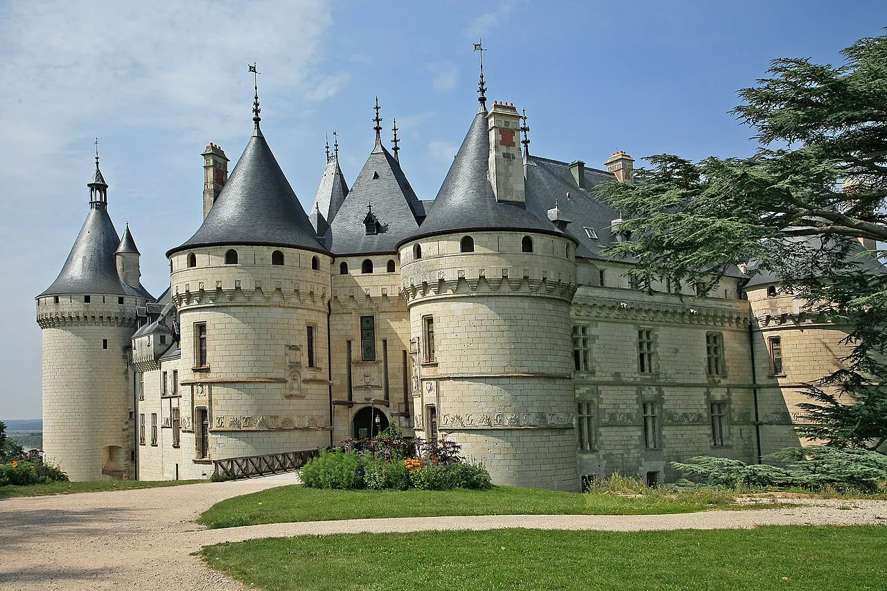 The pointed slate towers and white stone walls of the Château de Chaumont-sur-Loire beside cedar trees