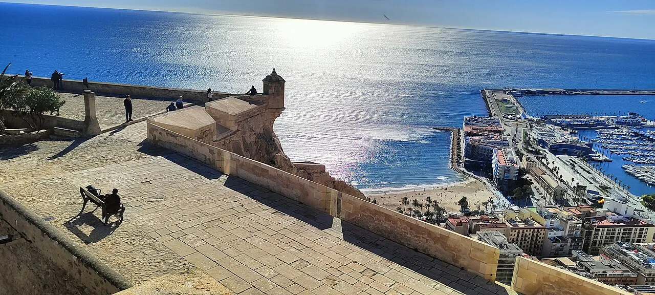 Sunlit view from the ramparts of Santa Bárbara Castle over Alicante's beach, port and the Mediterranean