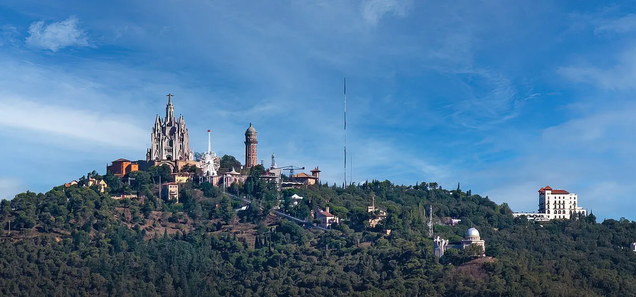Tibidabo hilltop with the Sagrat Cor church above wooded slopes, seen from across Barcelona