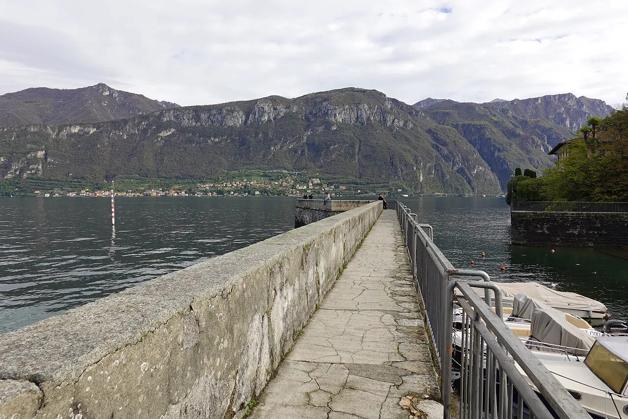 Narrow stone jetty at Punta Spartivento in Bellagio, facing the mountains across Lake Como