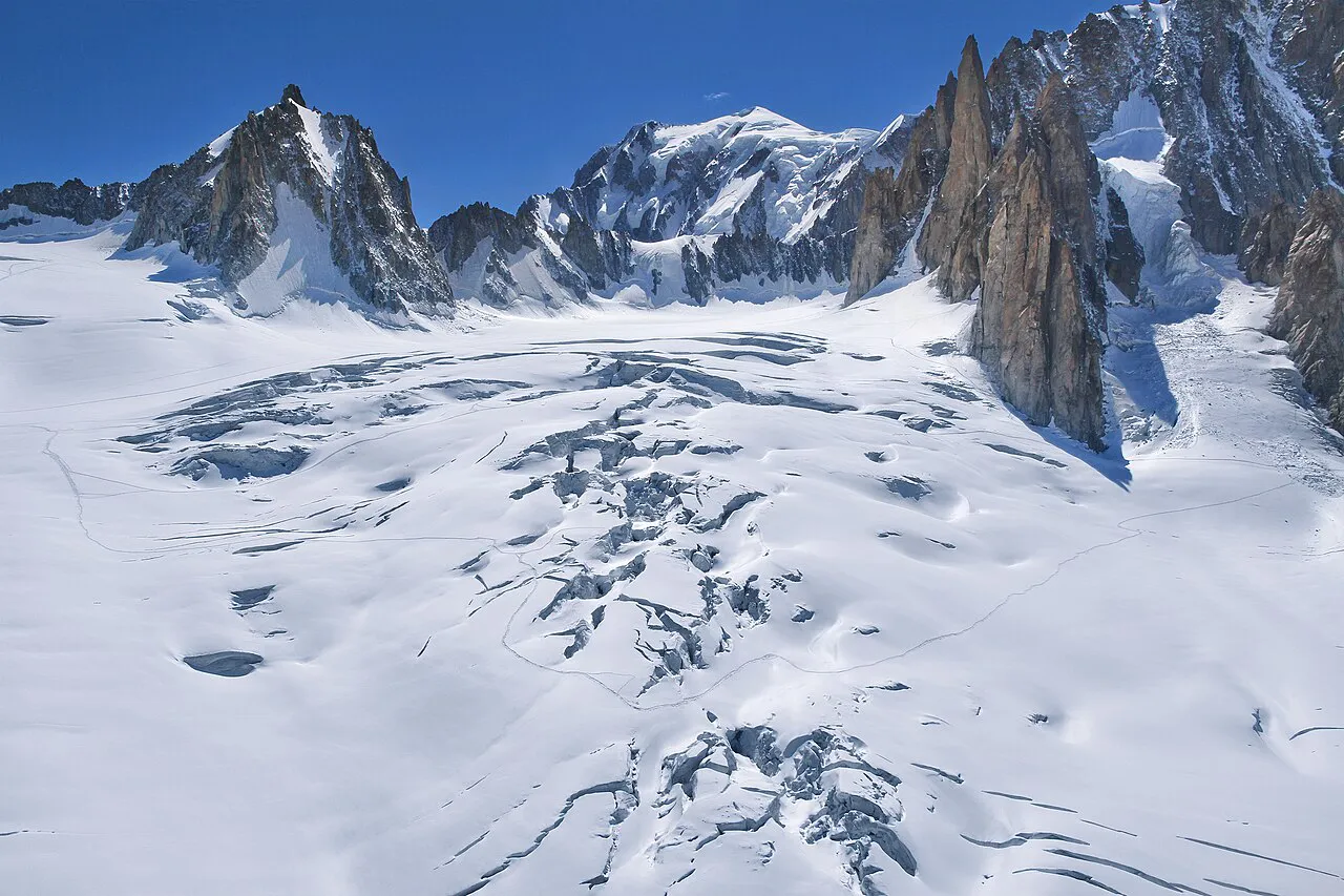 Crevassed Glacier du Géant beneath granite spires, with Mont Blanc on the skyline above Chamonix