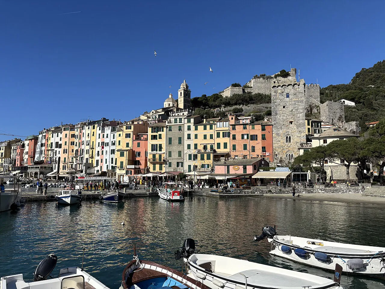 Pastel harbourfront houses and moored boats in Porto Venere with the Doria Castle above