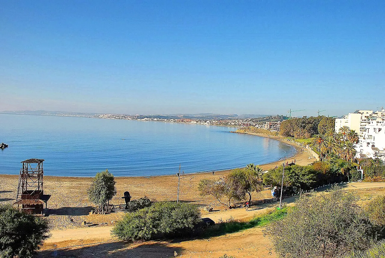 Curving bay of Playa del Cristo in Estepona with calm water and a lifeguard tower