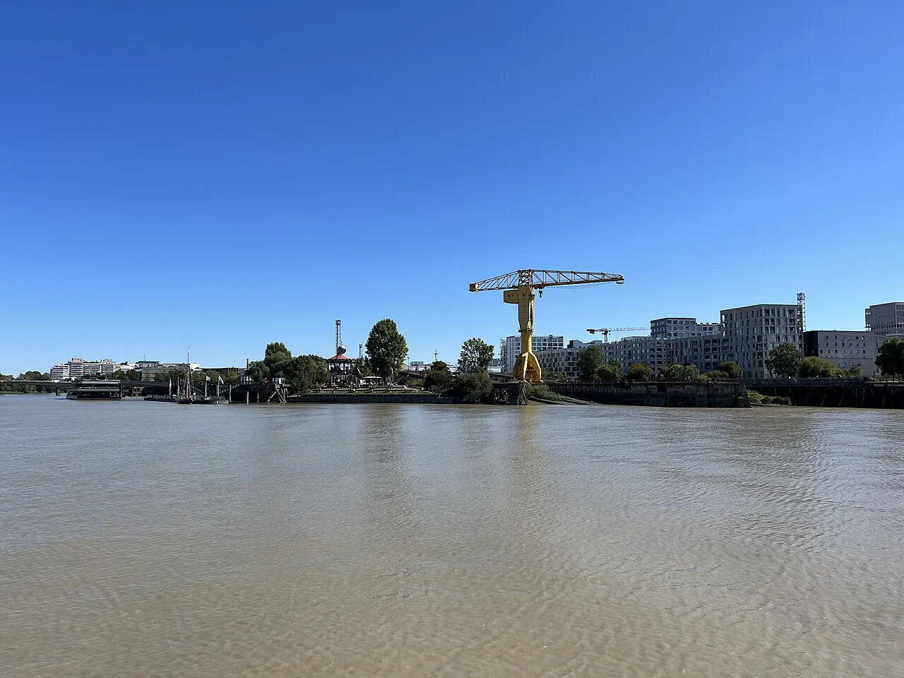 Yellow Titan crane and modern buildings on the Île de Nantes seen across the Loire under a clear blue sky