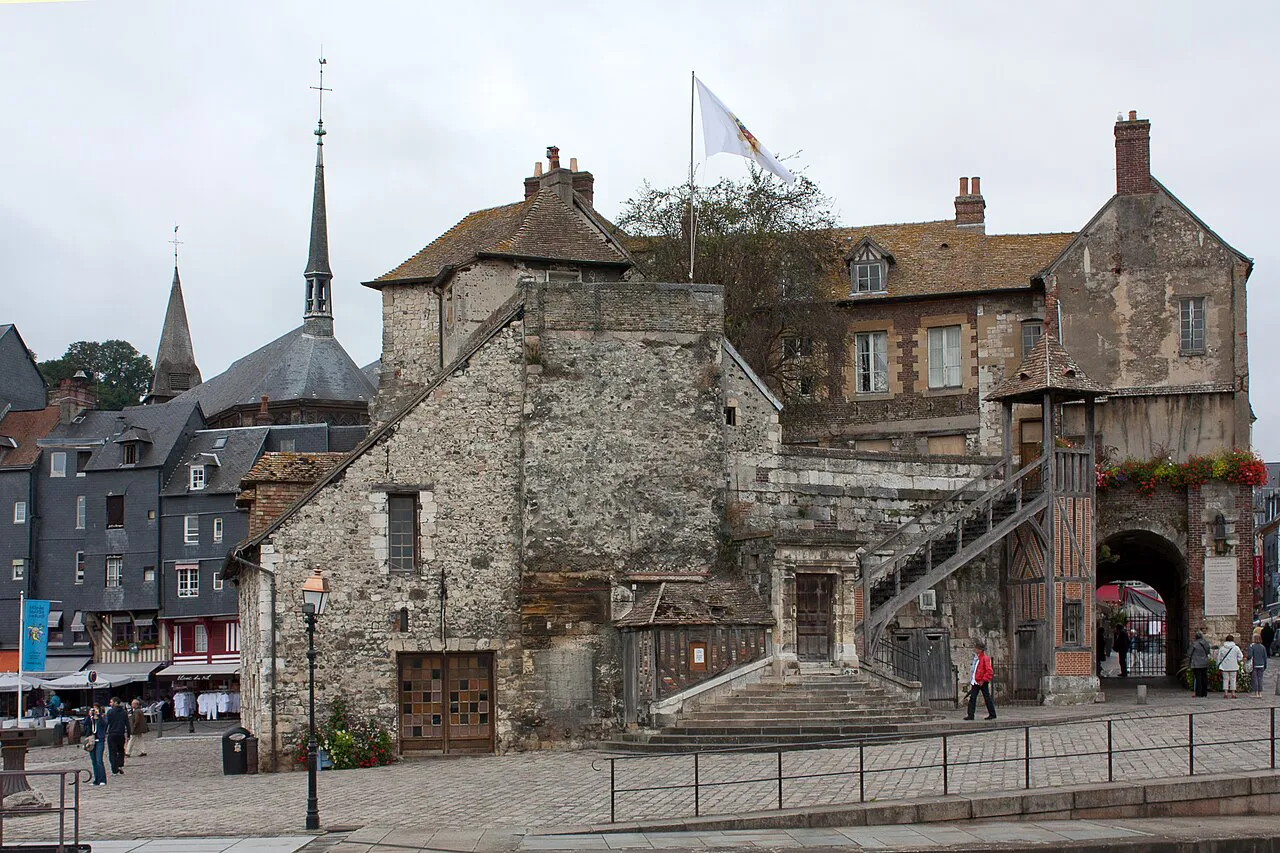 Old stone Lieutenance building on Honfleur’s harbour, with the Sainte-Catherine spire behind