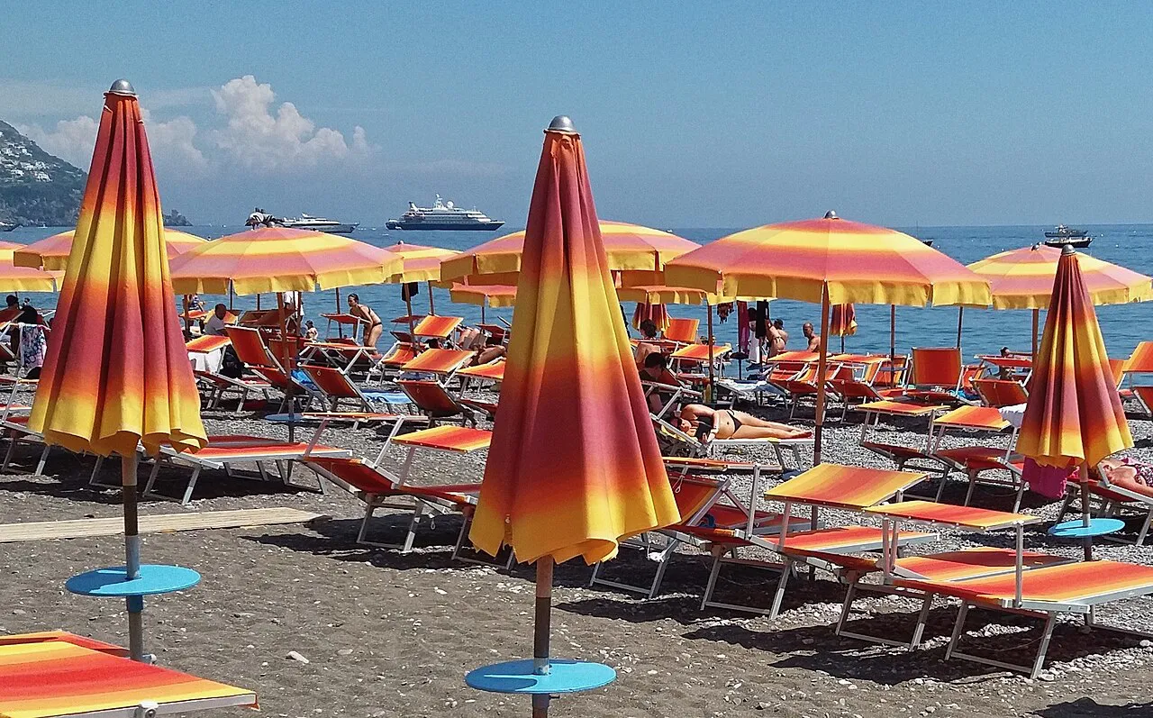 Rows of furled orange and yellow striped parasols on the Spiaggia Grande beach in Positano