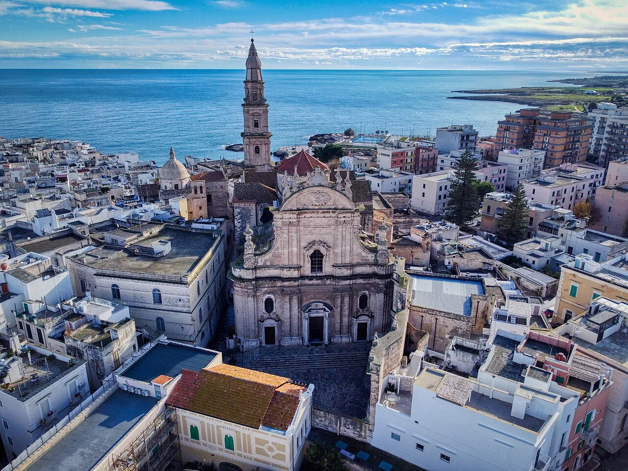 Aerial view over Monopoli’s pale rooftops to the cathedral bell tower and the Adriatic