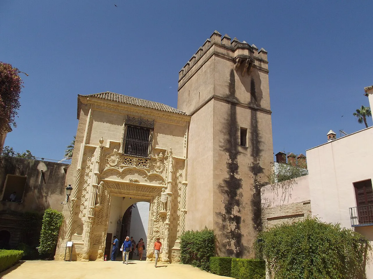 Renaissance stone gateway beside a crenellated tower in the gardens of the Real Alcázar, Seville