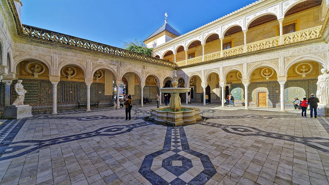 Arcaded courtyard of Casa de Pilatos with patterned paving, statues and a central fountain, Seville