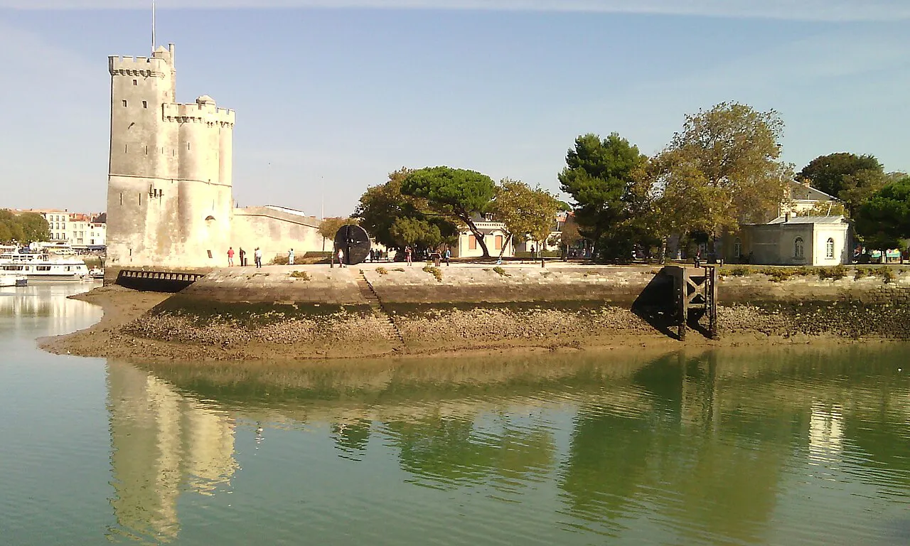 Tour Saint-Nicolas reflected in calm harbour water beside the Gabut quarter of La Rochelle